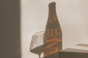 Shadow of a glass of wine and a glass bottle casted on the wall